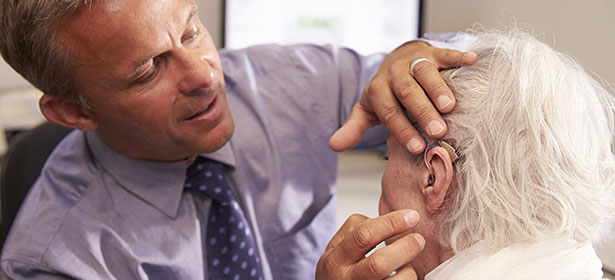 Audiologist fits a hearing aid 