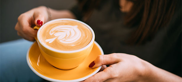 A latte in a yellow coffee cup