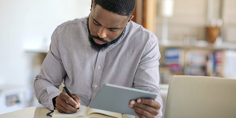 Man using a tablet and taking notes