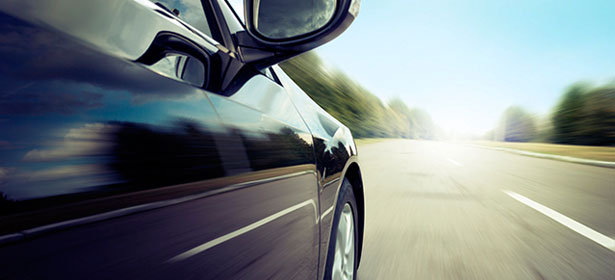 Dark coloured car on fast road